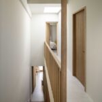 Corridor with wooden staircase, balustrade of vertical slats, wooden doors and rooflight