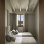 Bedroom with two beds, green cushions, white-beamed ceiling and mountain views