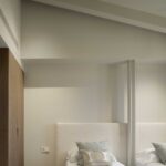 Bedroom detail with two beds, light upholstered headboards, wooden wardrobe and ceiling spotlights