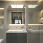Bathroom with wall-hung greyish-green basin, illuminated mirror, glass shower and rooflight in the ceiling