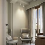 Study with two upholstered wing armchairs, wooden desk and French window with curtains