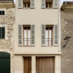 Three-storey street façade with greyish-green shutters, wooden door and wooden gate