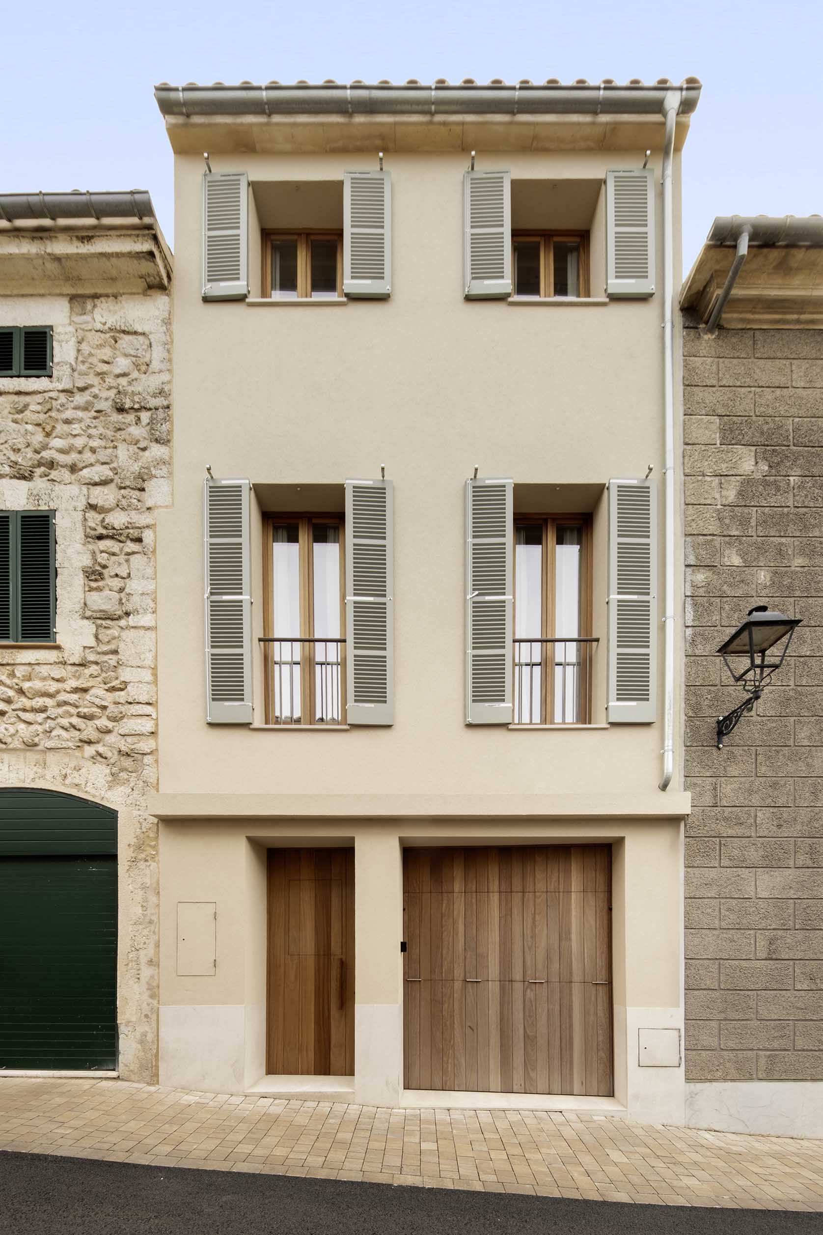 Three-storey street façade with greyish-green shutters, wooden door and wooden gate