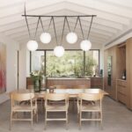 Comedor y cocina con armarios de madera, lámpara de esferas y ventanal hacia el patio