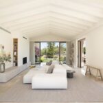 Salón visto desde el otro extremo, con sofá modular, estantería empotrada, chimenea y puertas al jardín