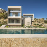 Villa LF91CG01 mit Fassade aus beigen Baukörpern, Pool und Natursteinmauer im Vordergrund