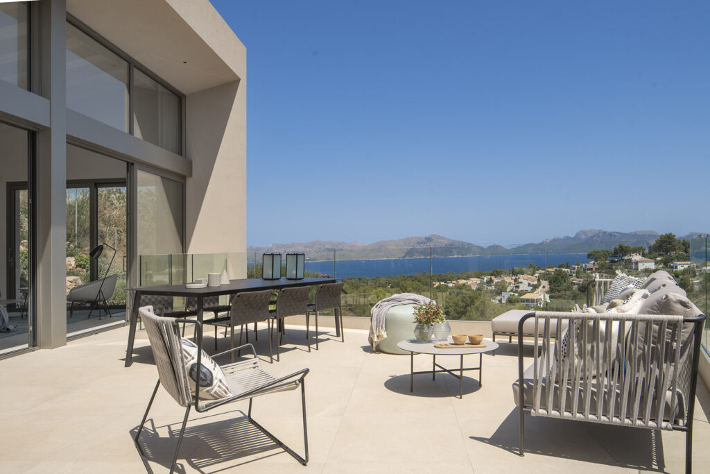 Terrasse der Villa LF91CG01 mit Essbereich und Außensofas sowie Blick auf Bucht und Berge