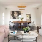 Rundes Esszimmer, vom Wohnzimmer aus gesehen, mit goldener Lampe, Schwarz-Weiß-Porträt und weißen Bögen