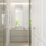 Baño con lavabo de mármol sobre mueble gris claro, espejo alto y mampara de cristal