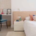 Dormitorio infantil con cabecero color melocotón, escritorio empotrado, silla azul de terciopelo y osito de peluche
