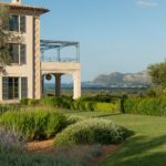 Esquina de la casa con soportal y terraza con pérgola, jardín y vistas al mar y montañas
