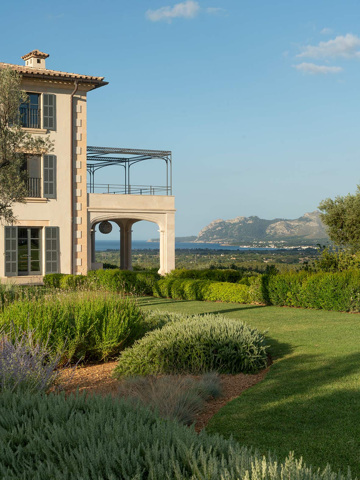 Esquina de la casa con soportal y terraza con pérgola, jardín y vistas al mar y montañas