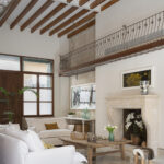 Salón de techos altos con vigas vistas, balcón de forja, chimenea de piedra y sofá blanco