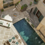 Vista aérea del patio con piscina, tumbonas, mesa de comedor, escalera y fachada de piedra