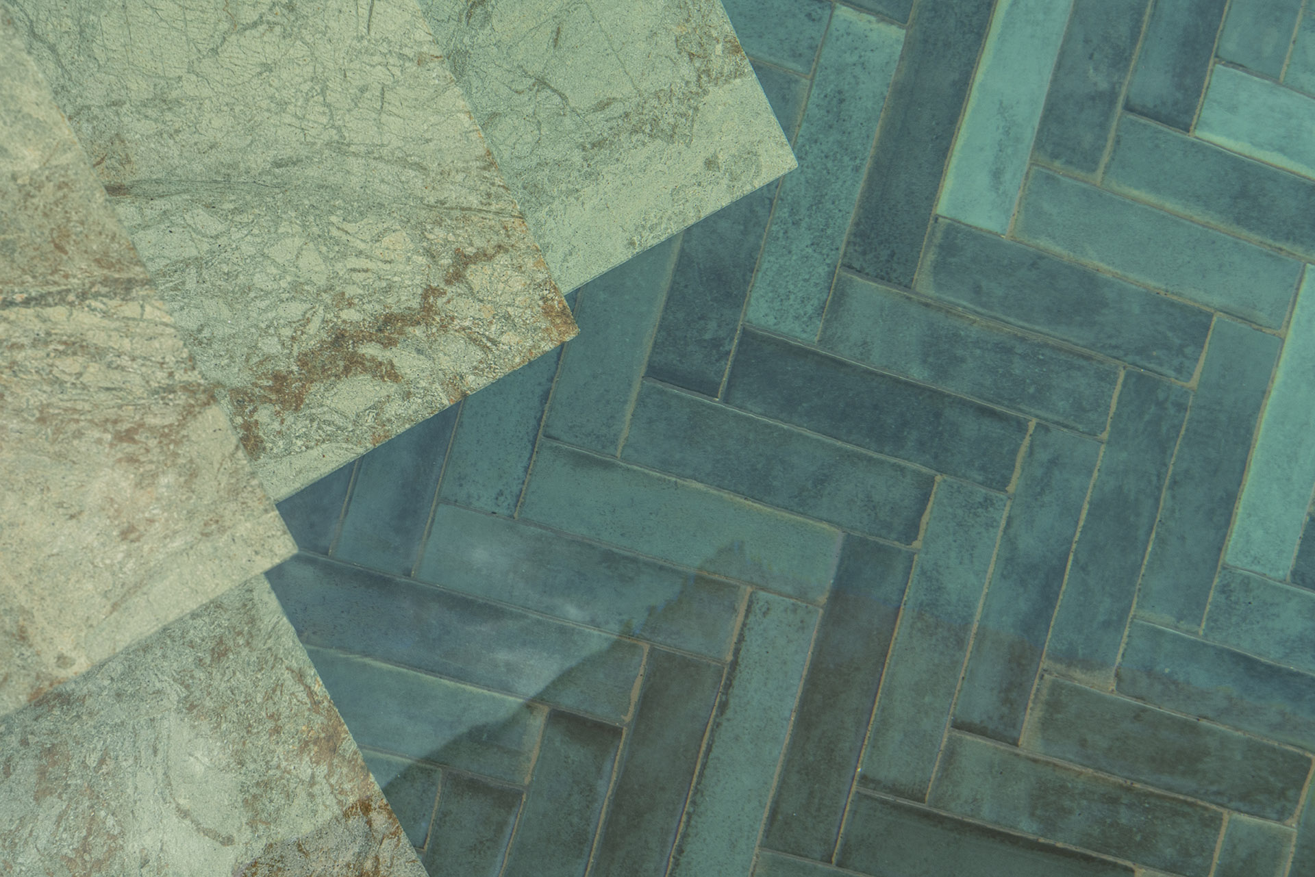 Detalle de piezas de mármol verdoso junto a azulejos turquesa dispuestos en espiga