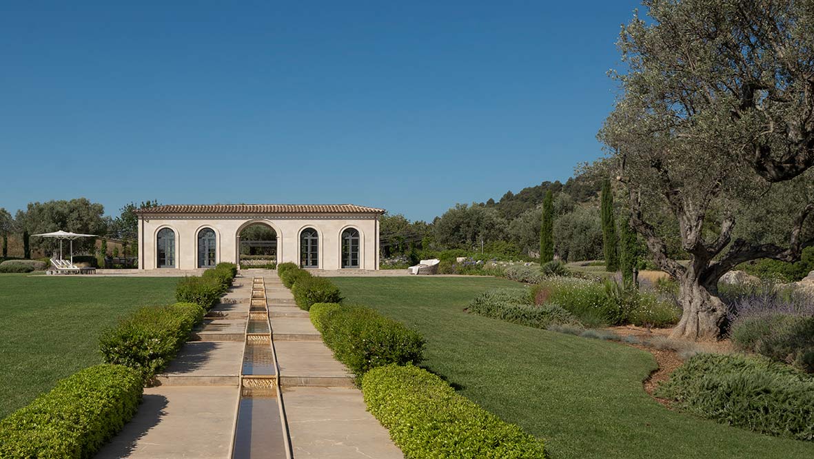 Steinweg mit Wasserkanal zwischen Hecken, der zum Pavillon mit Bögen führt