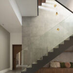 Dunkle Treppe mit Glasgeländer, Wand aus grauem Feinsteinzeug, bernsteinfarbenen Hängeleuchten und Holzbank