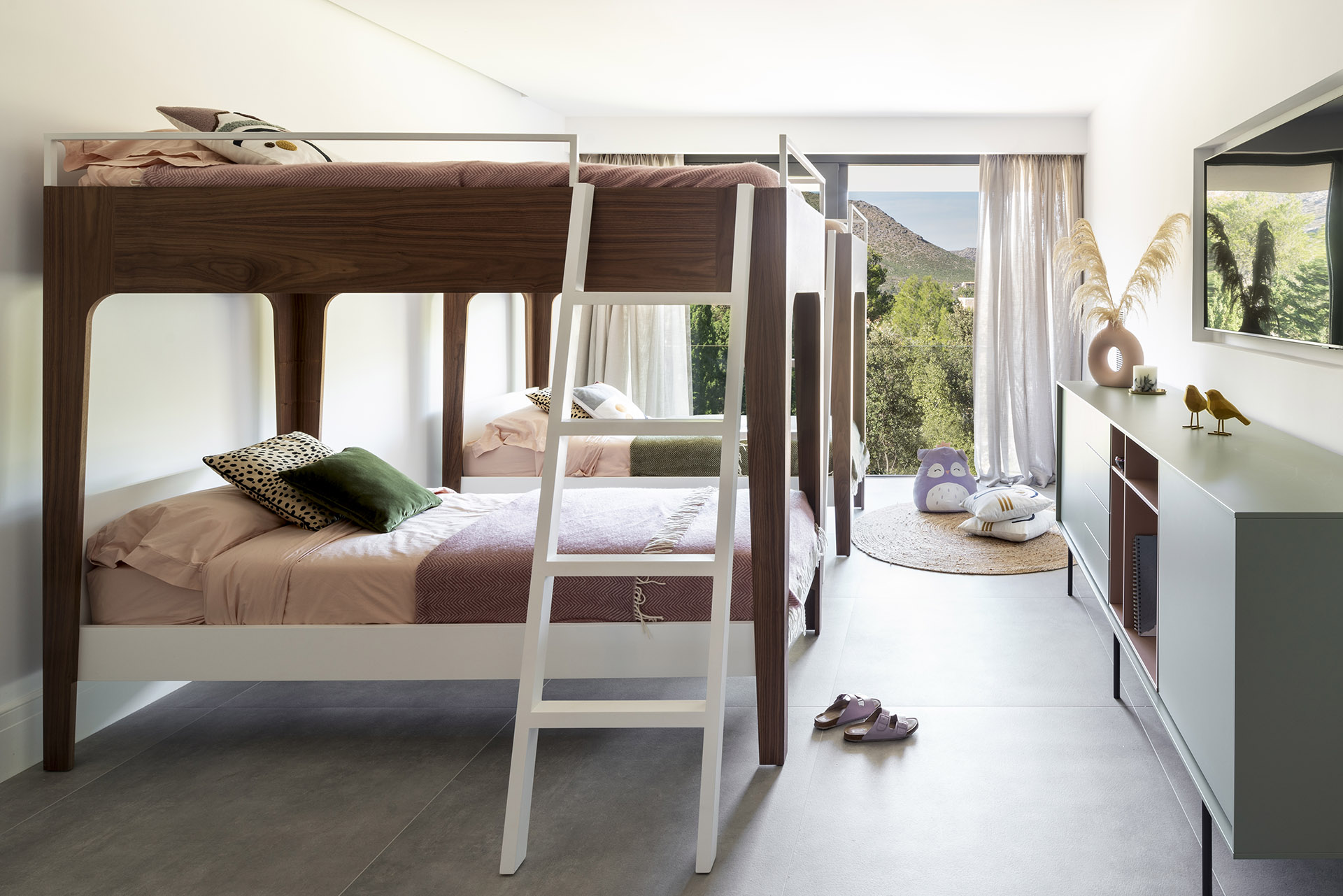 Kinderzimmer mit Etagenbetten in Nussbaum und Weiß, grauem Boden und Blick auf die Berge