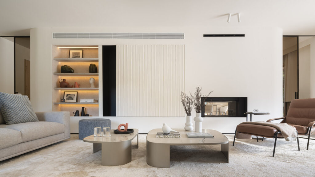 Wohnzimmer mit zweiseitiger Kaminwand, beleuchtetem Regal, geriffelter Wandverkleidung und Couchtischen