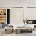 Wohnzimmer mit zweiseitiger Kaminwand, beleuchtetem Regal, geriffelter Wandverkleidung und Couchtischen