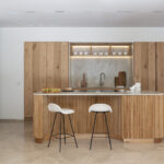 Plano frontal de la cocina con armarios altos de madera, balda iluminada sobre el fregadero y horno integrado