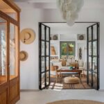 Glass and iron doors open to the living room, with translucent lamp, straw hats and jute rug