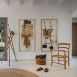 White entrance hall with two abstract paintings, rush chair, jute rug and pale seamless flooring