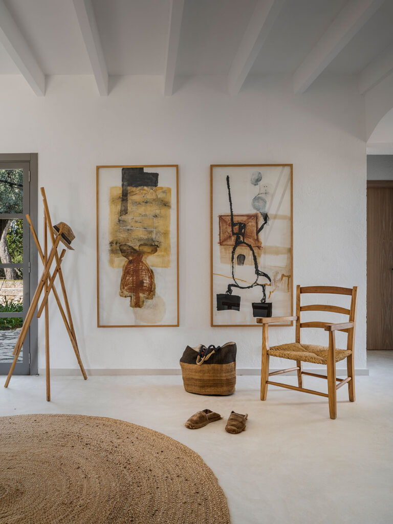 White entrance hall with two abstract paintings, rush chair, jute rug and pale seamless flooring