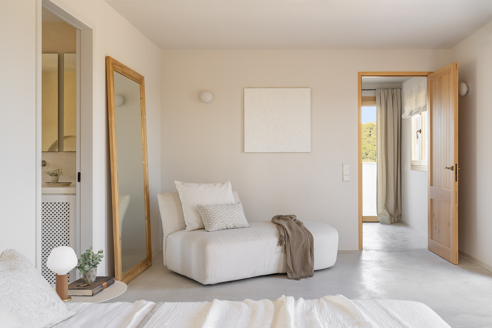 Schlafzimmer mit weißer Chaiselongue, Standspiegel mit Holzrahmen und offener Tür zum Flur