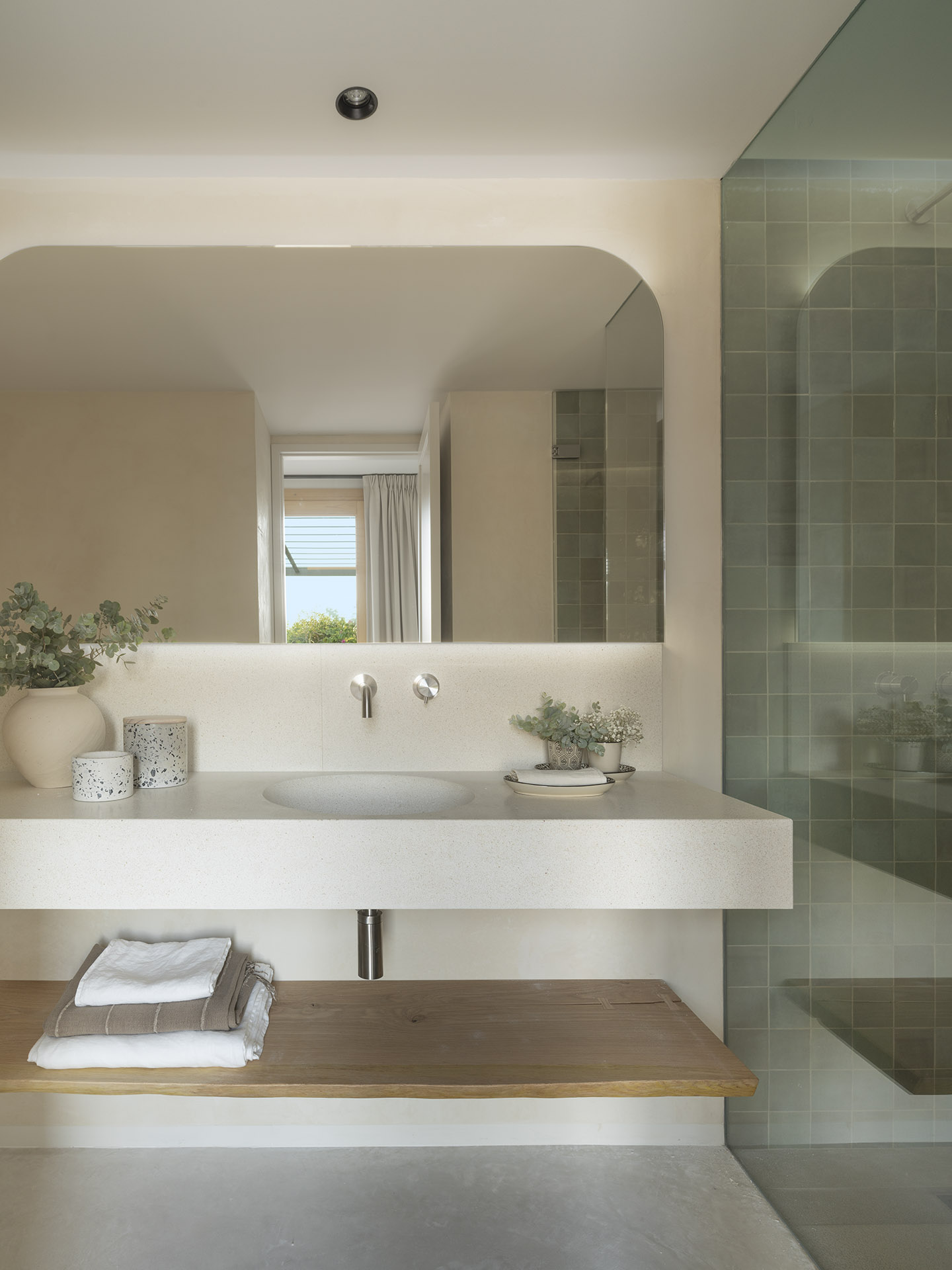 Terrazzo-Waschtisch, Spiegel mit abgerundeten Ecken, Holzablage mit Handtüchern und eine geflieste Dusche