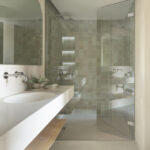 Badezimmer mit Dusche aus grünen Zellige-Fliesen, Terrazzo-Waschtisch, Holzablage und Duschwand aus Glas