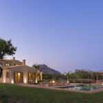 Panoramablick am Abend mit einem Baum im Vordergrund, dem Haus, dem Pool und der Chill-out-Zone