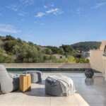 Terrace with swimming pool, grey pouffes, masonry oven and views of the wooded hillside