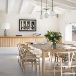 Dining room with weathered wooden table, light wood chairs and white globe lamps