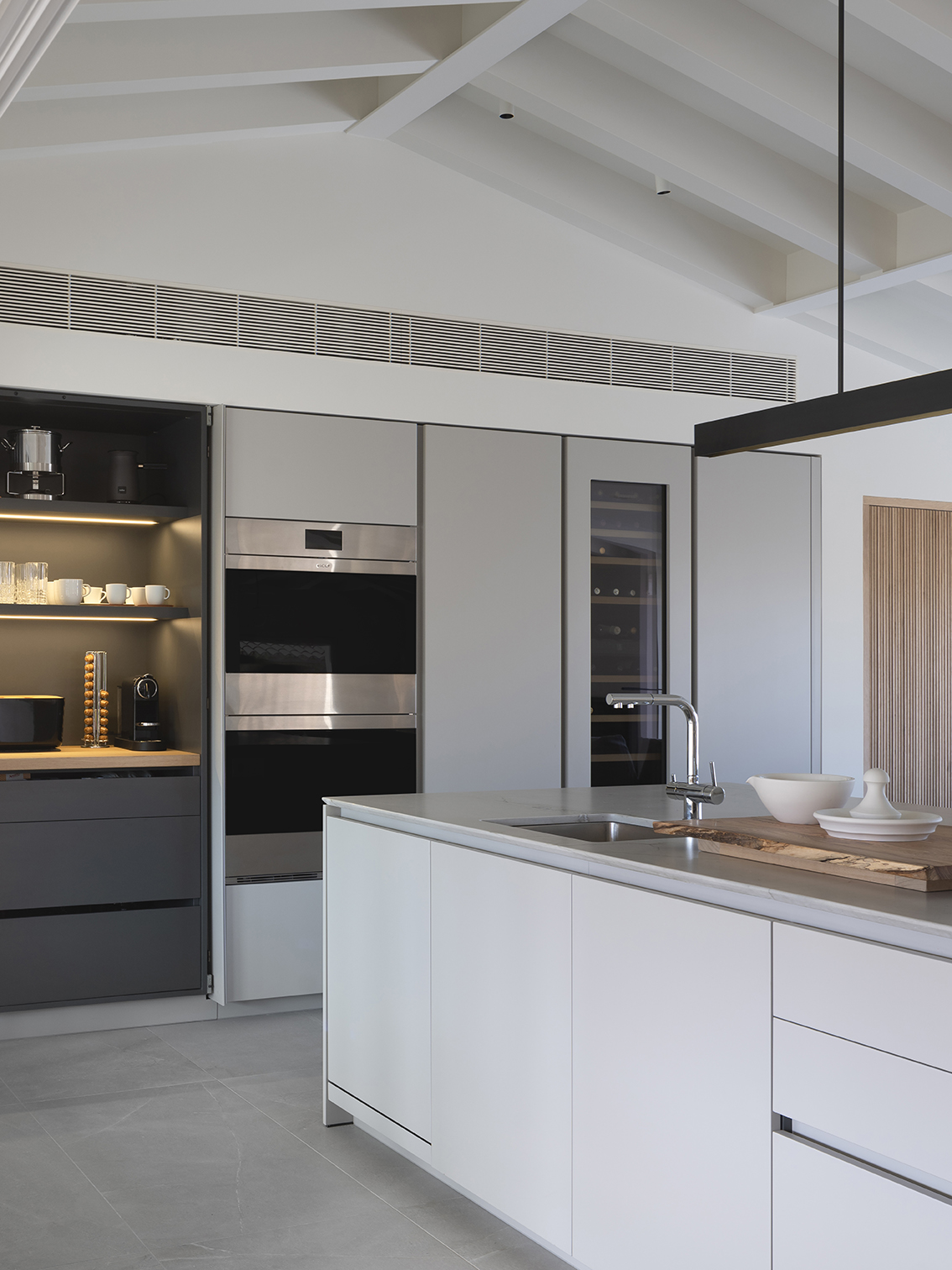 Tall grey units with steel ovens, wine cooler and an illuminated coffee corner