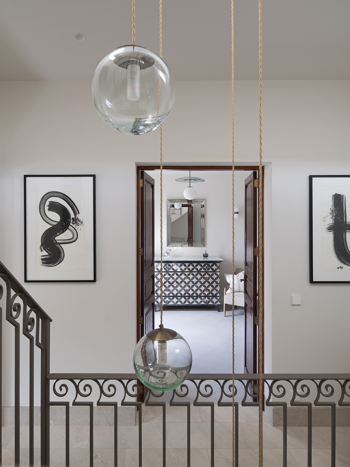 Landing with abstract black and white paintings, glass lamps and dark wooden doors