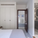 White bedroom with built-in wardrobe and en suite bathroom with a grey tiled shower