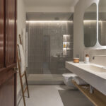 Bathroom with shower in glazed grey tiles, wall-hung toilet, light worktop and illuminated mirrors