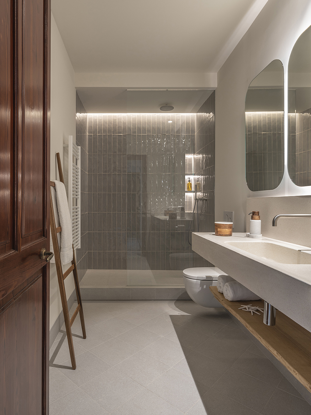 Bathroom with shower in glazed grey tiles, wall-hung toilet, light worktop and illuminated mirrors