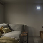 Cinema room with grey sofa, mustard cushions, wall-mounted television and low wooden unit