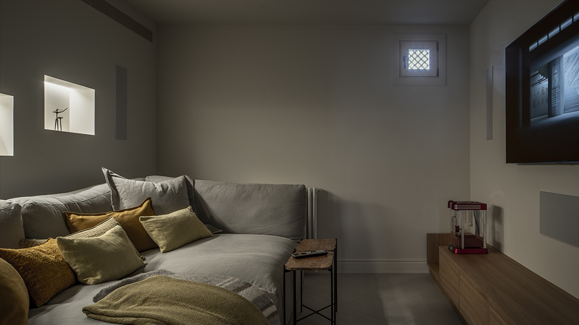 Cinema room with grey sofa, mustard cushions, wall-mounted television and low wooden unit