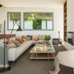Bright living room with grey corner sofa, terracotta cushions, reddish sideboard, fireplace and grey windows