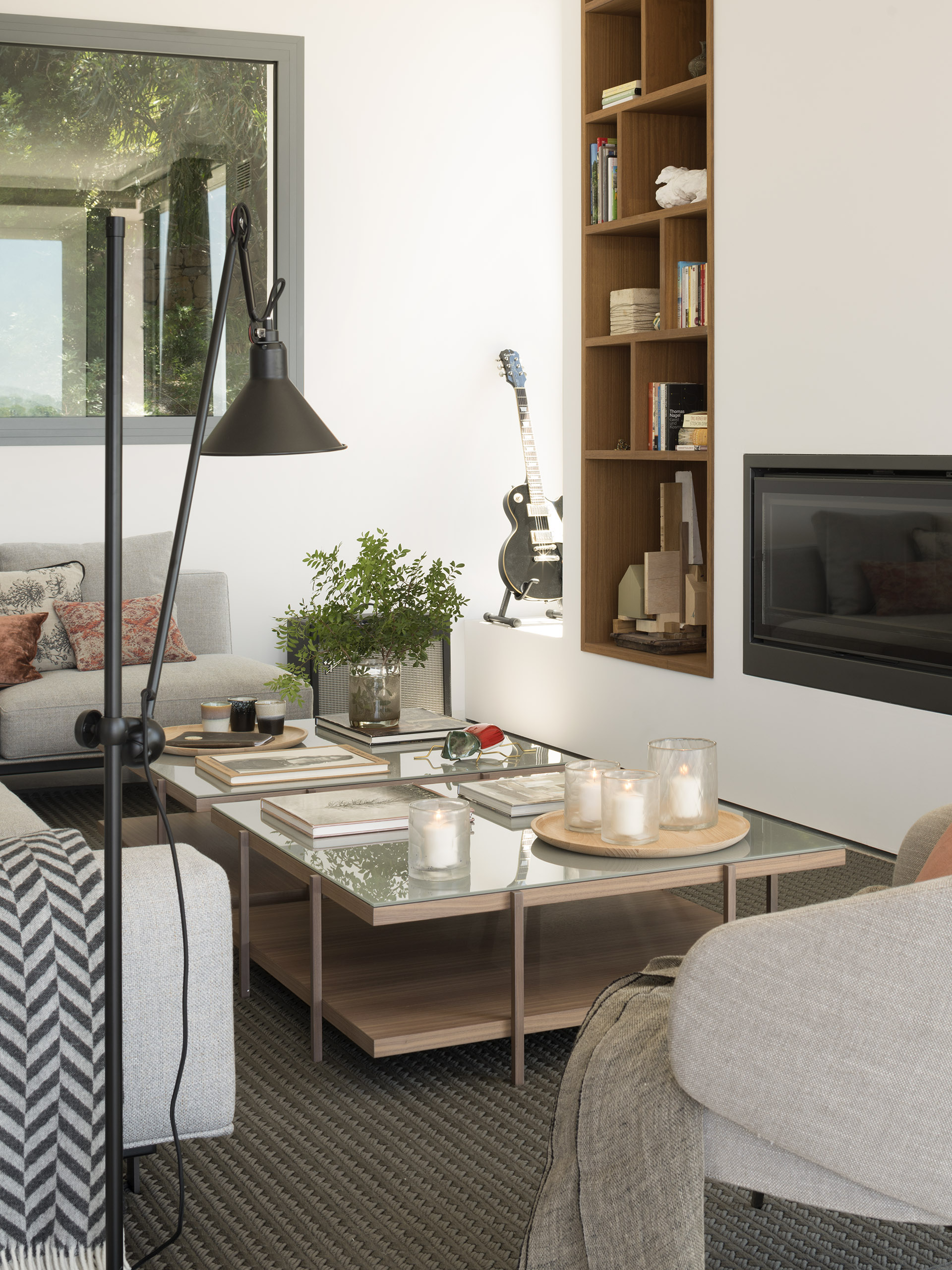 Living room detail with floor lamp, coffee tables with candles, built-in shelving and fireplace