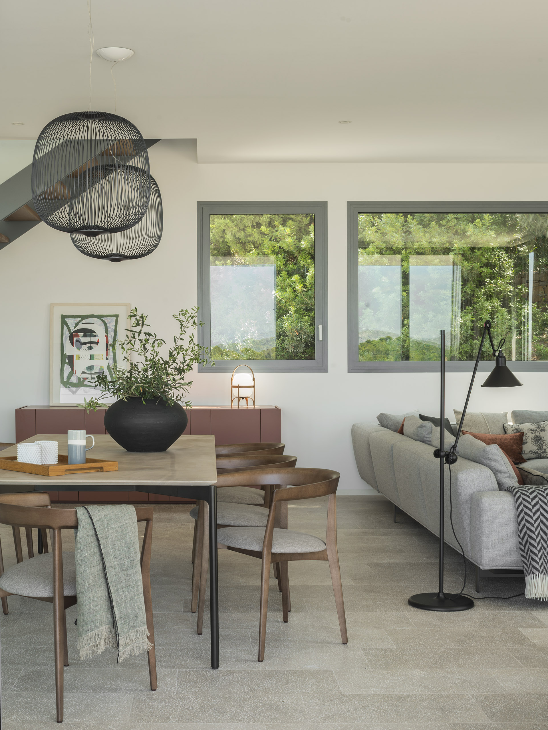 Dining room with wooden table, upholstered chairs, black wire pendant lights and terracotta sideboard