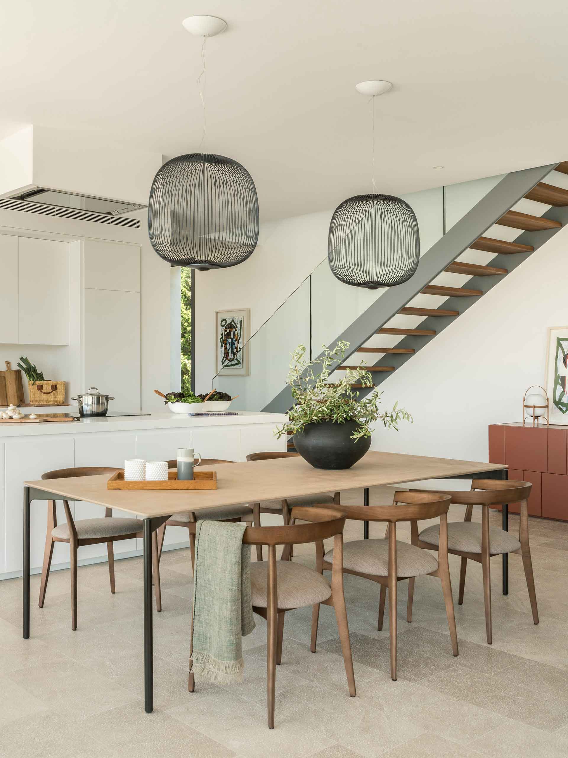 Dining area with wooden chairs next to the kitchen and the staircase with timber treads