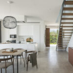 Open-plan space with kitchen, dining area, staircase and garden access at the back, painting above the sideboard