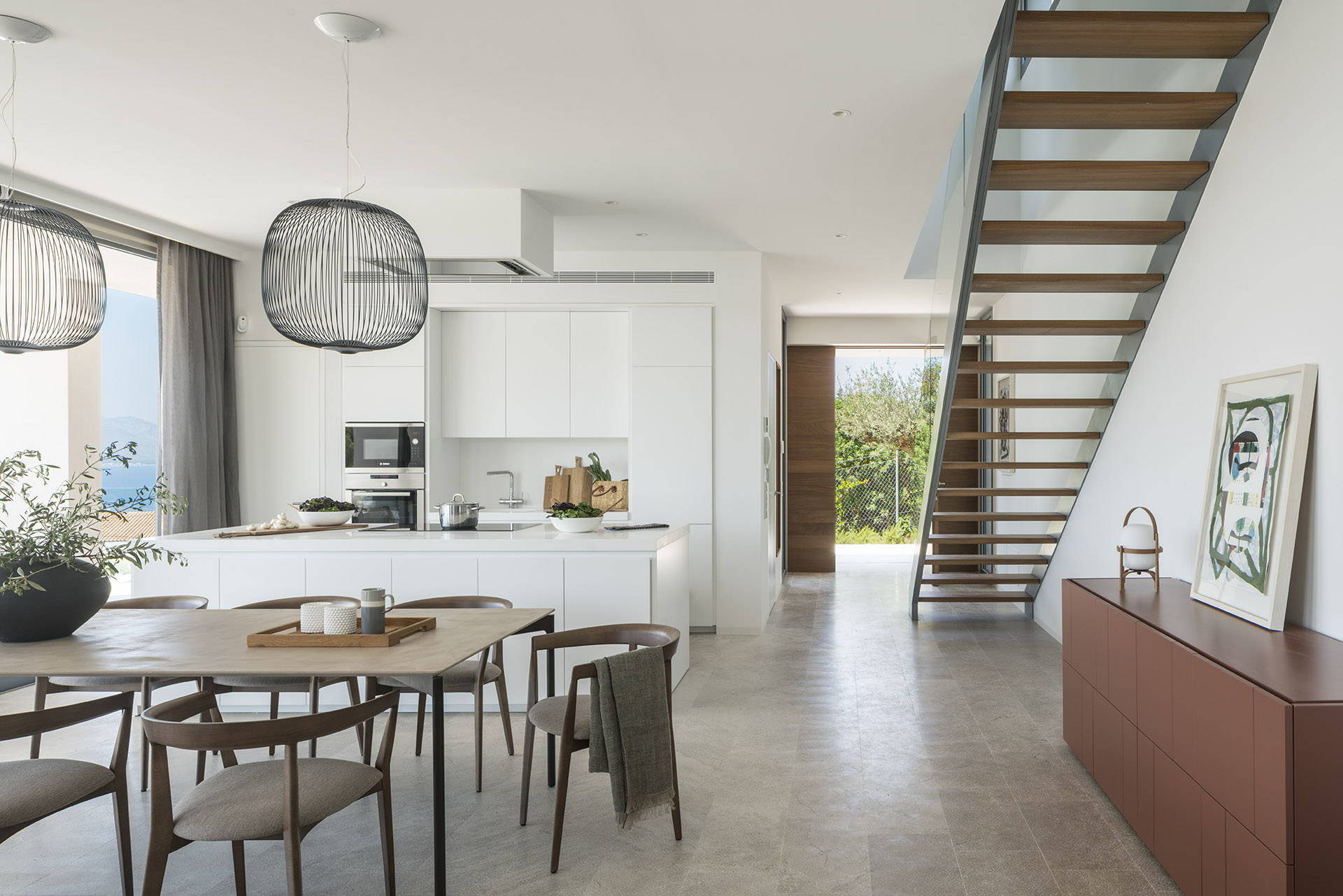Open-plan space with kitchen, dining area, staircase and garden access at the back, painting above the sideboard