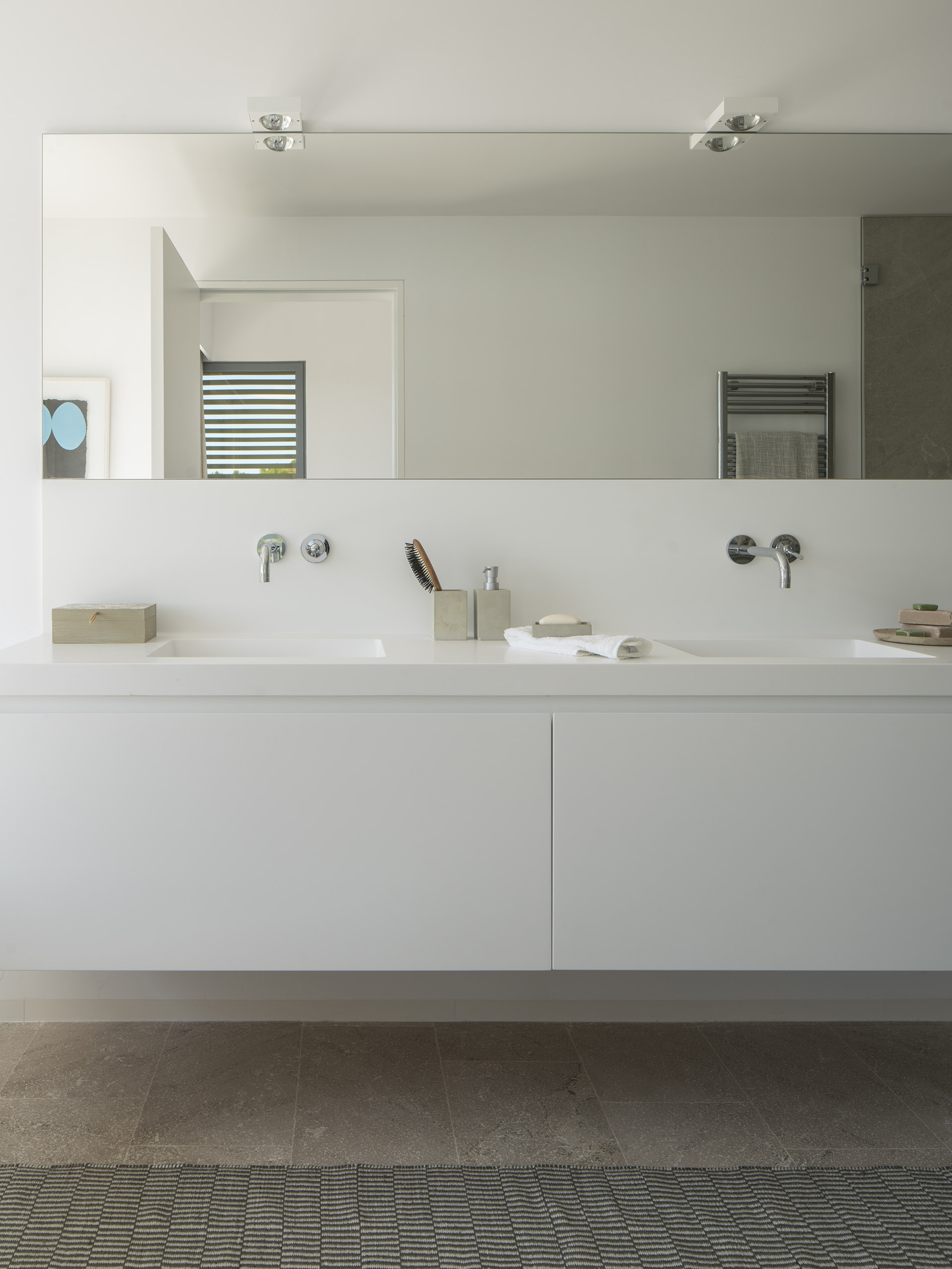 Bathroom with white wall-hung double basin, large mirror, concealed taps and stone floor