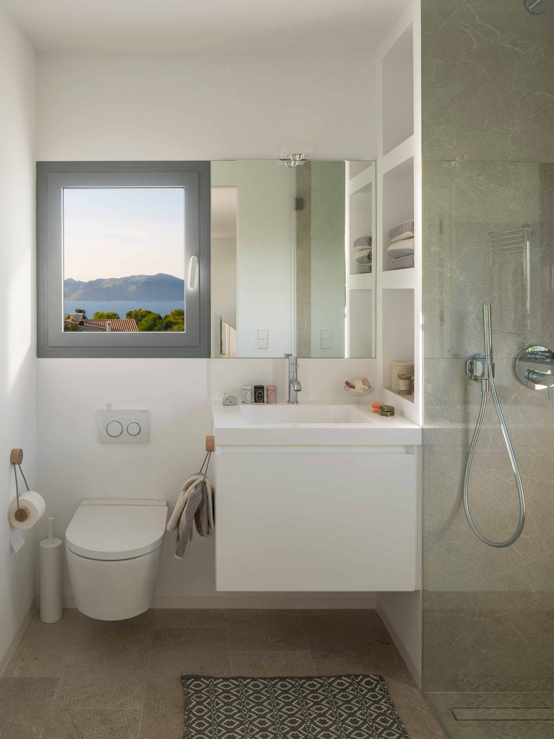 Bathroom with window and sea views, wall-hung toilet, white basin and glazed shower