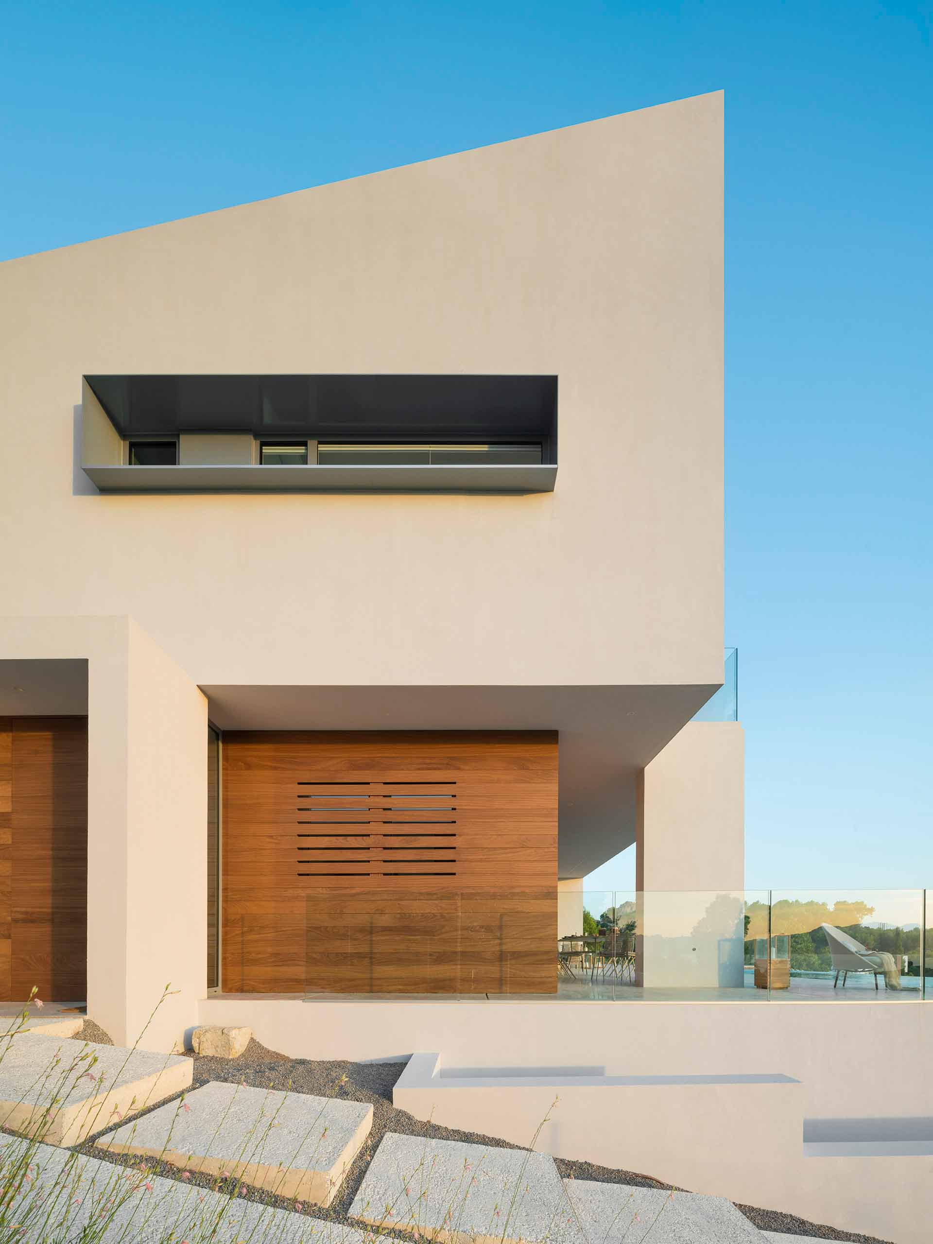 Façade detail with timber cladding, overhang, elongated window and stone steps